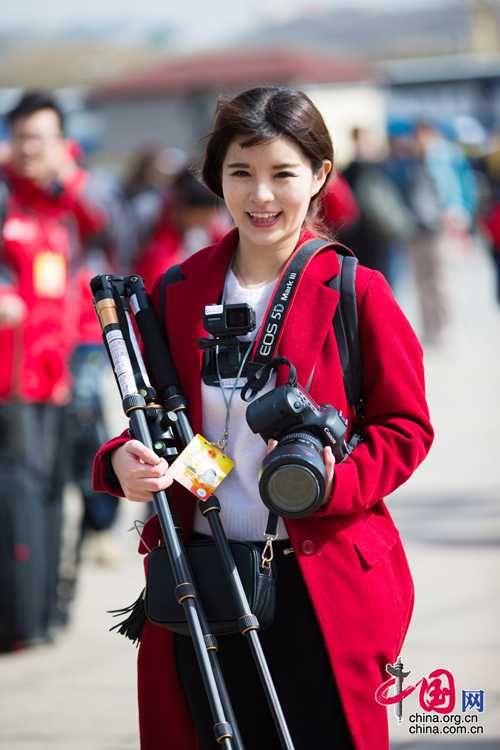 2016年兩會(huì)，人民大會(huì)大堂前，一位笑容燦爛的紅衣女記者正步入大會(huì)堂。中國(guó)網(wǎng) 鄭亮 攝
